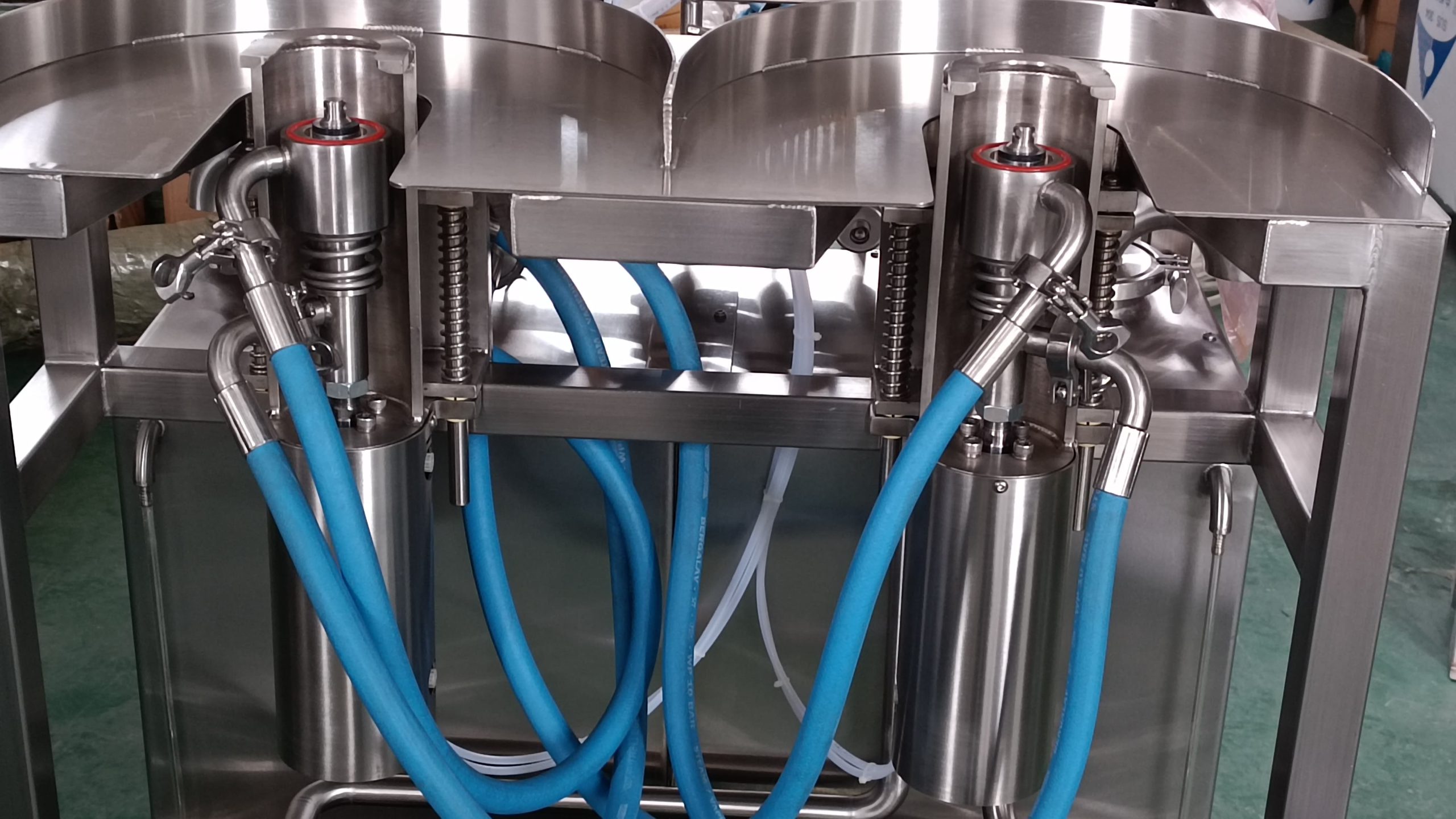 Underside of a keg washer with blue hoses and cleaning heads