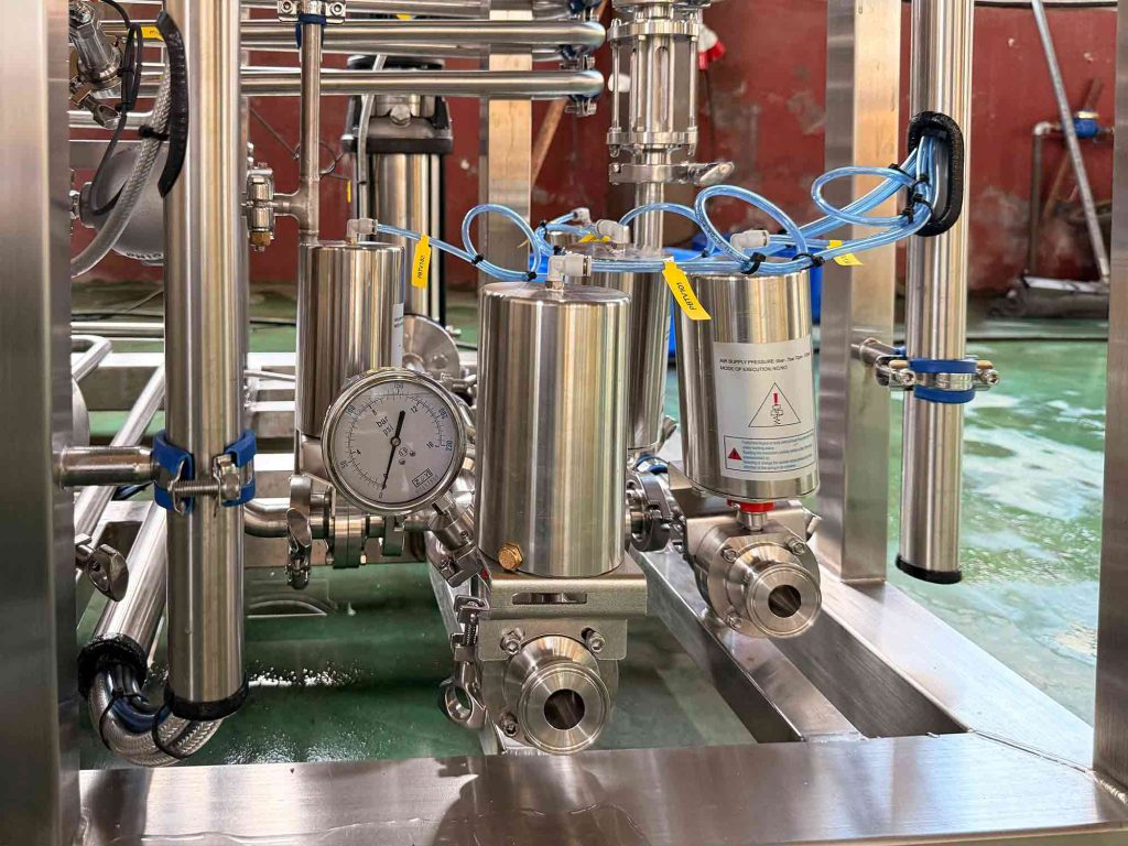Close-up of pressure gauges and sanitary filter housings on a pasteurizer skid